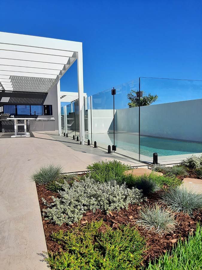 A Swimming Pool With a Glass Fence Around It — Full Circle Landscaping in Currumbin Valley, QLD
