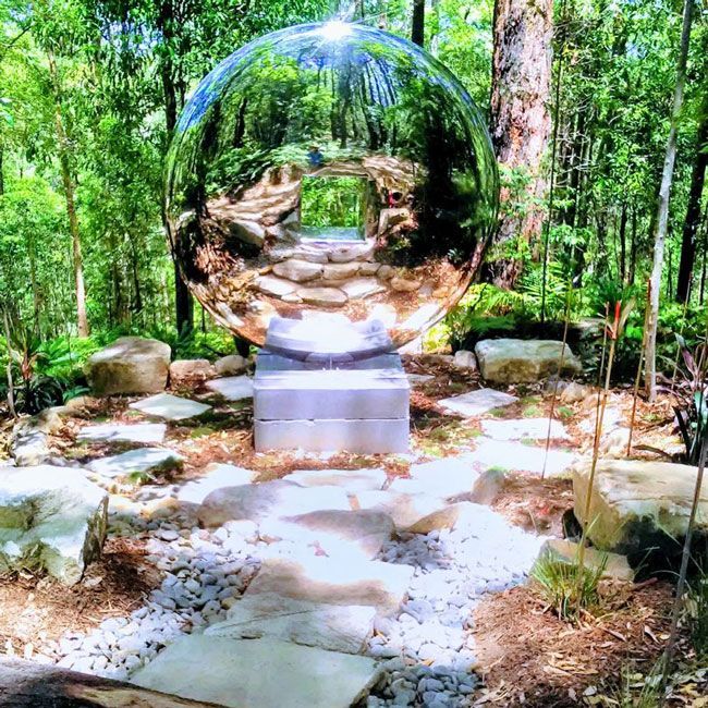 A Large Stainless Steel Sphere Is In The Middle Of A Forest — Full Circle Landscaping in Uki, NSW