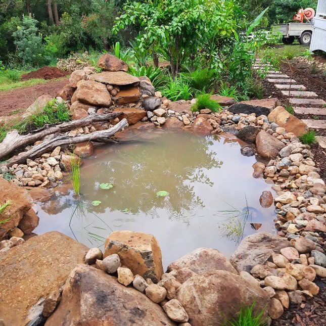 A Stone Walkway In A Garden Next To A House — Full Circle Landscaping in Uki, NSW