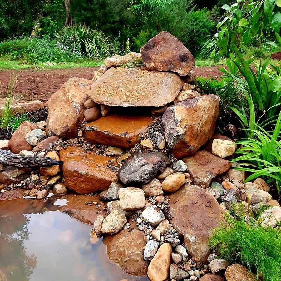 A Pile of Rocks is Surrounded by Water and Plants — Full Circle Landscaping in Tweed Heads, NSW