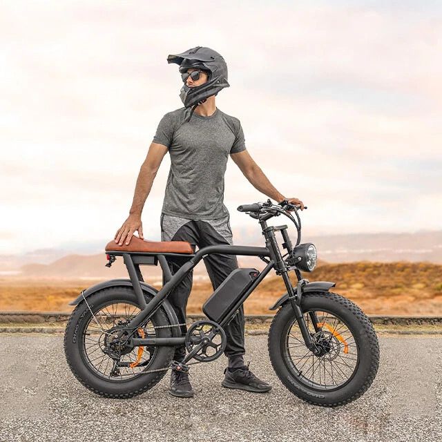 A man wearing a helmet is standing next to an electric bike.