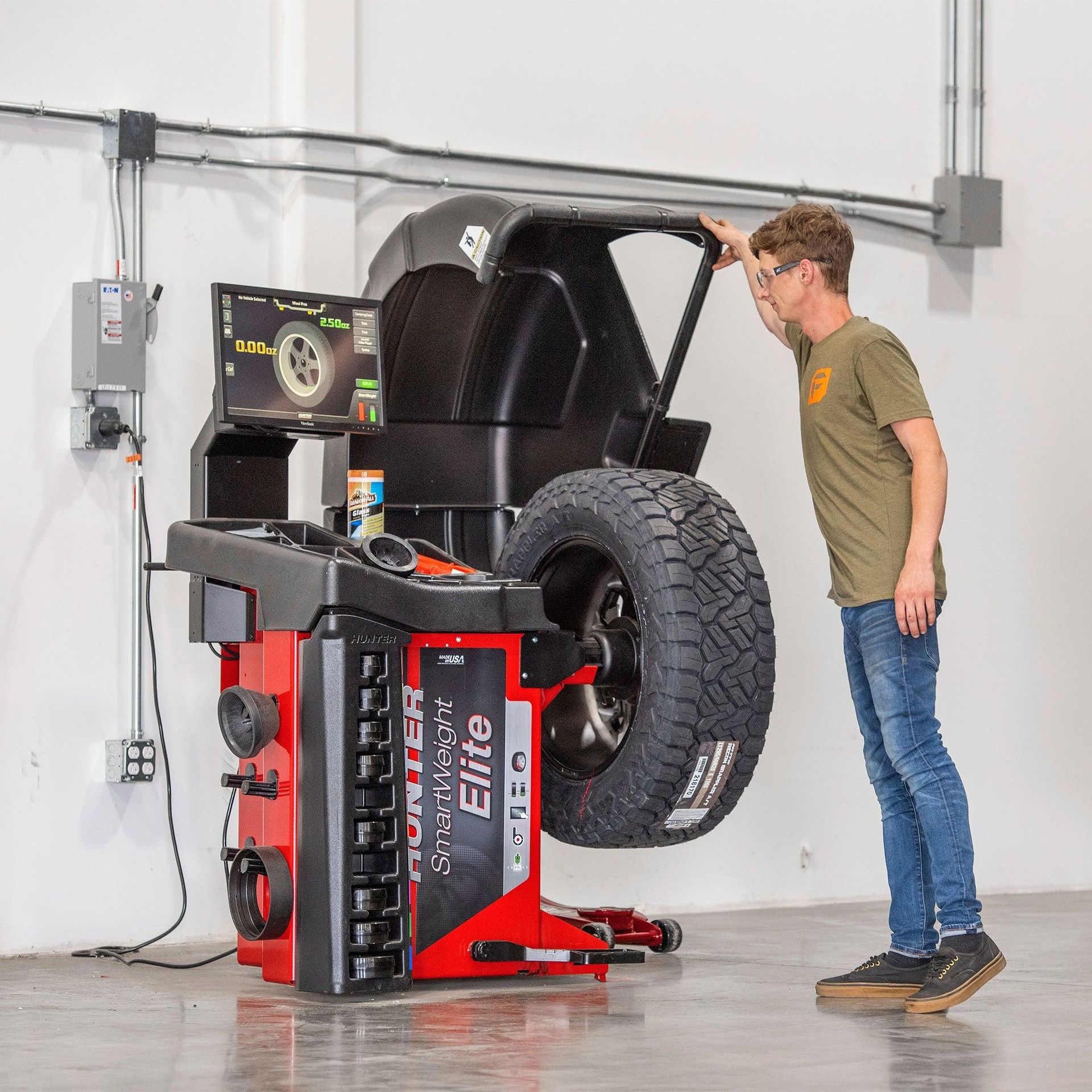 Person examining a lifted car on a tire machine in a garage workshop