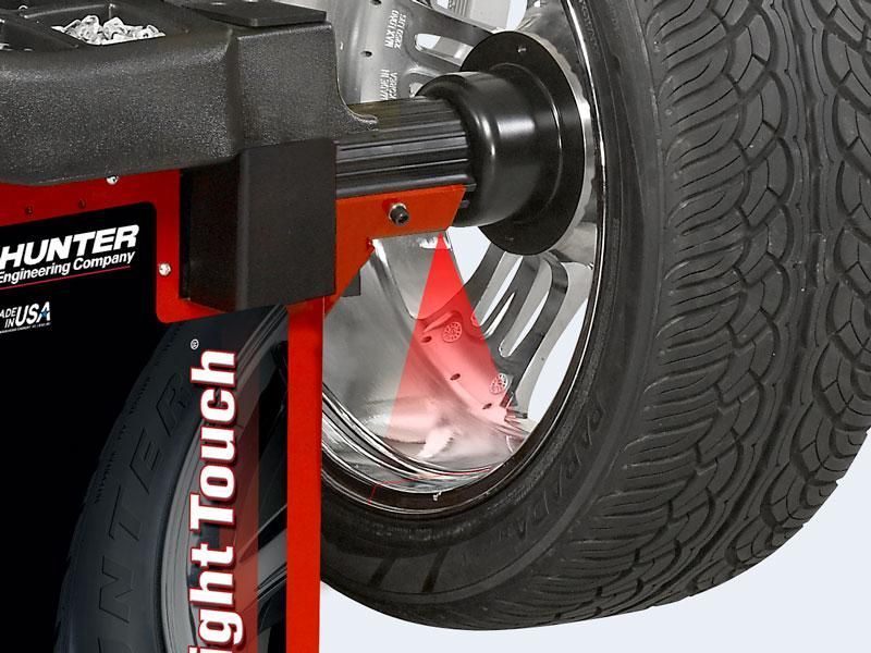 Wheel alignment machine measuring a car tire on a wheel balancer