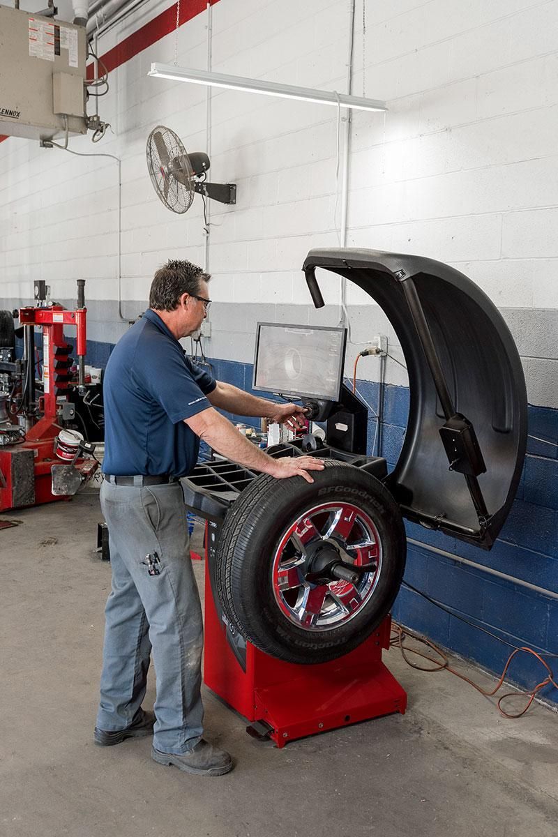 Mechanic using a wheel-balancing machine on a car tire in an auto shop