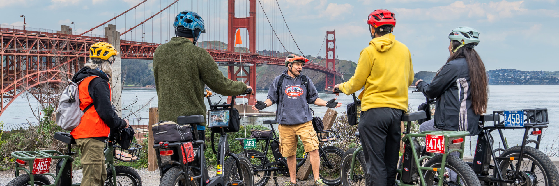 A group of people are riding bicycles in front of the San Francisco golden gate bridge.