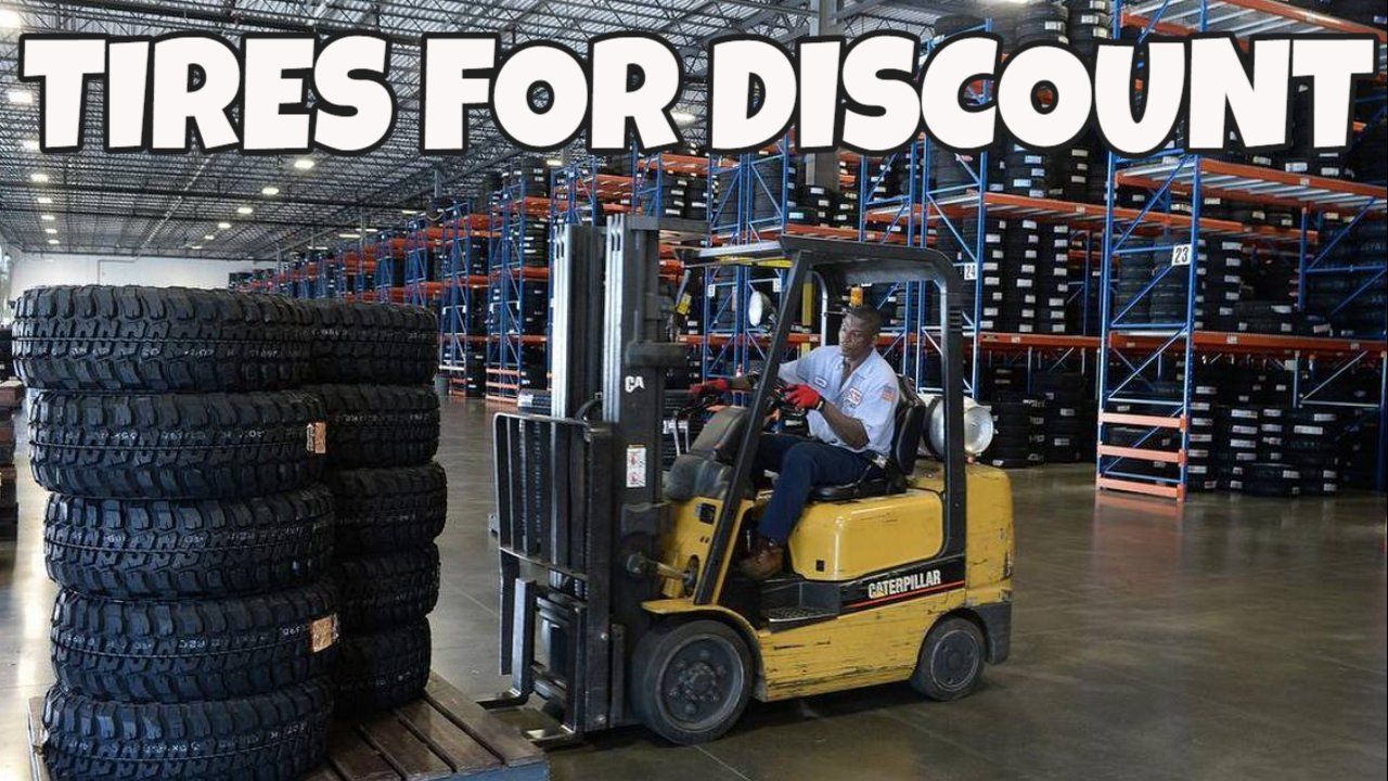 a man is driving a forklift in a warehouse filled with tires .