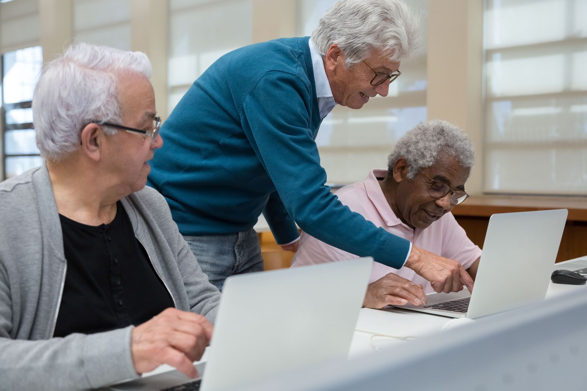 Three people using laptops together at a table in a bright room