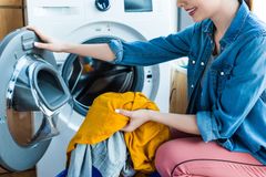 Donna che carica i vestiti in una lavatrice a carica frontale con un asciugamano giallo in vista