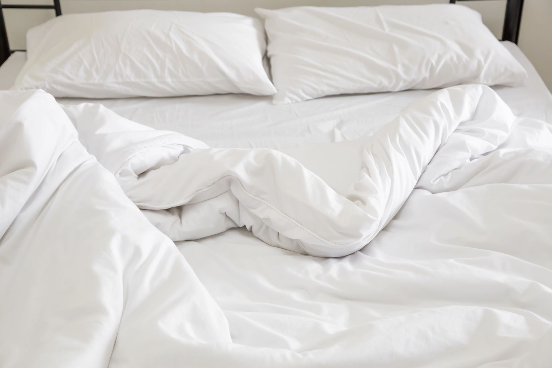 Letto bianco sfatto con cuscini e coperte stropicciate