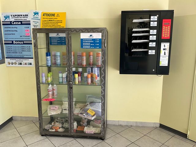Piccola hall con vetrina per la vendita di snack e bevande sulla sinistra e distributore automatico nero sulla destra.
