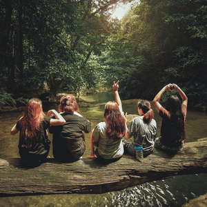a group of women are sitting on a log in the water