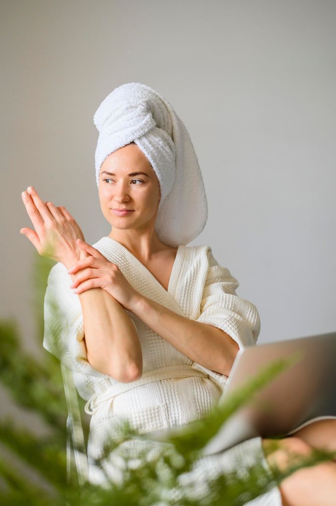 a woman with a towel wrapped around her head is sitting in front of a laptop