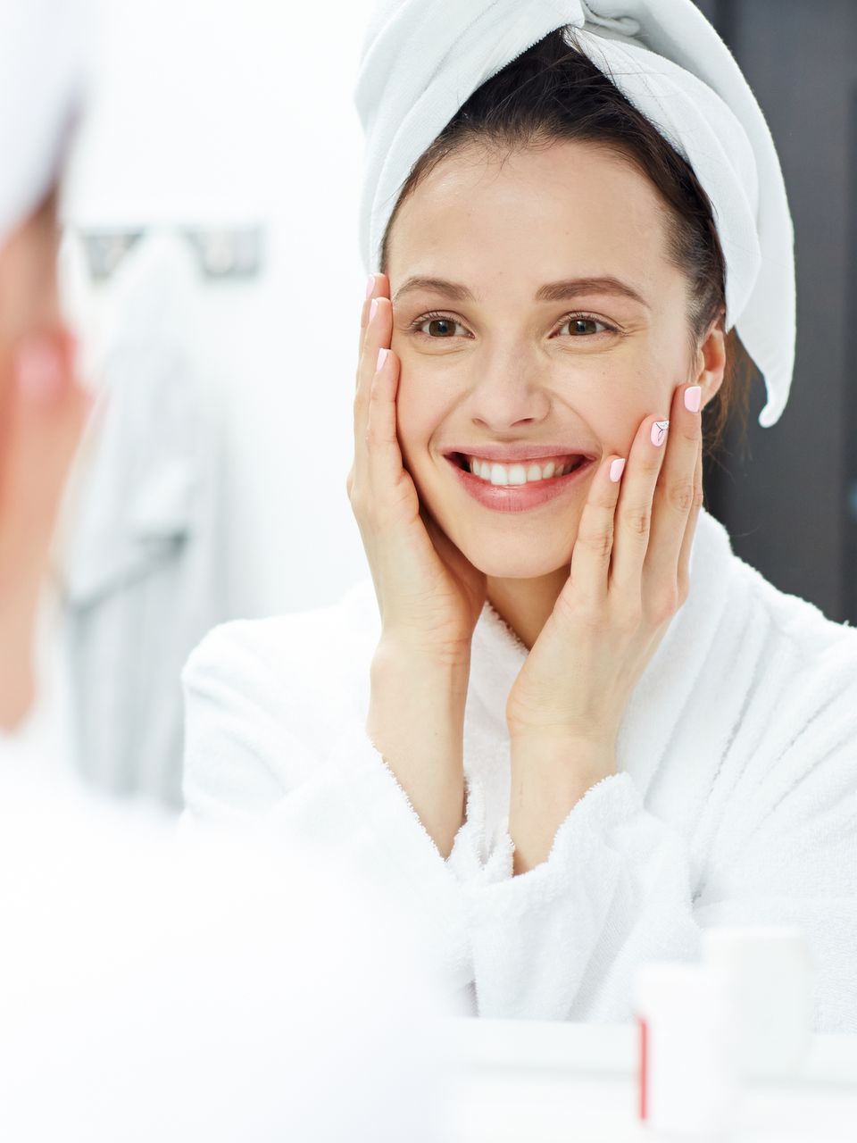 a woman with a towel wrapped around her head looks at herself in the mirror