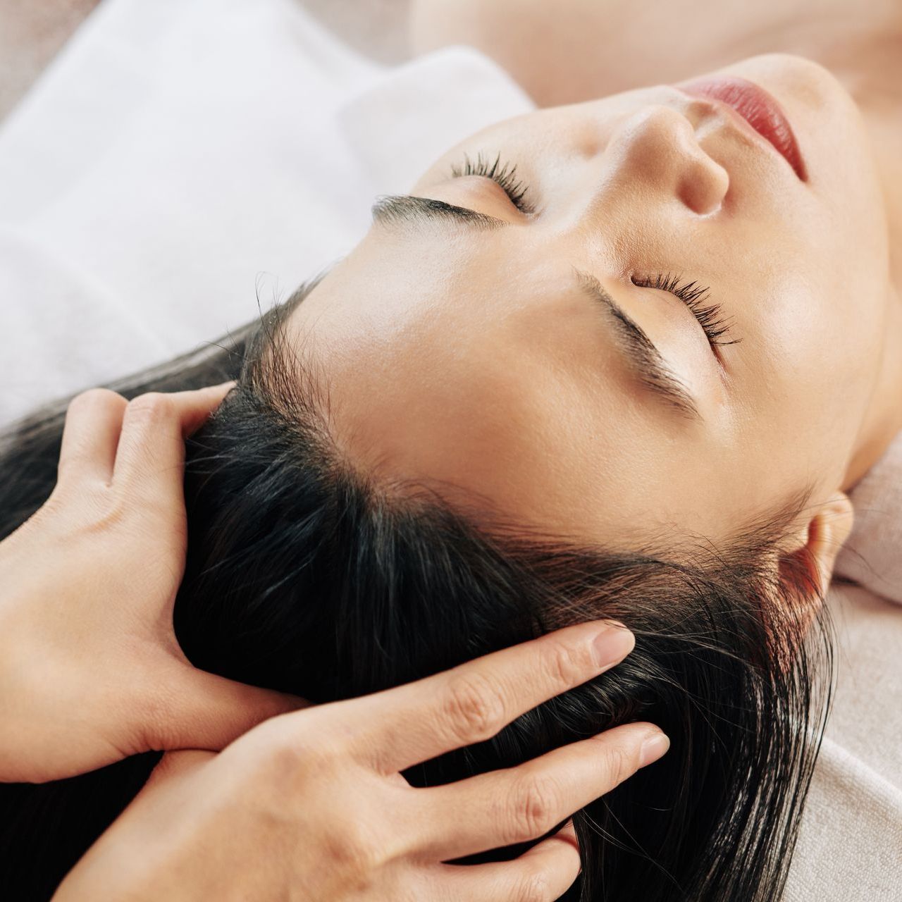 a woman with her eyes closed is getting her hair massaged