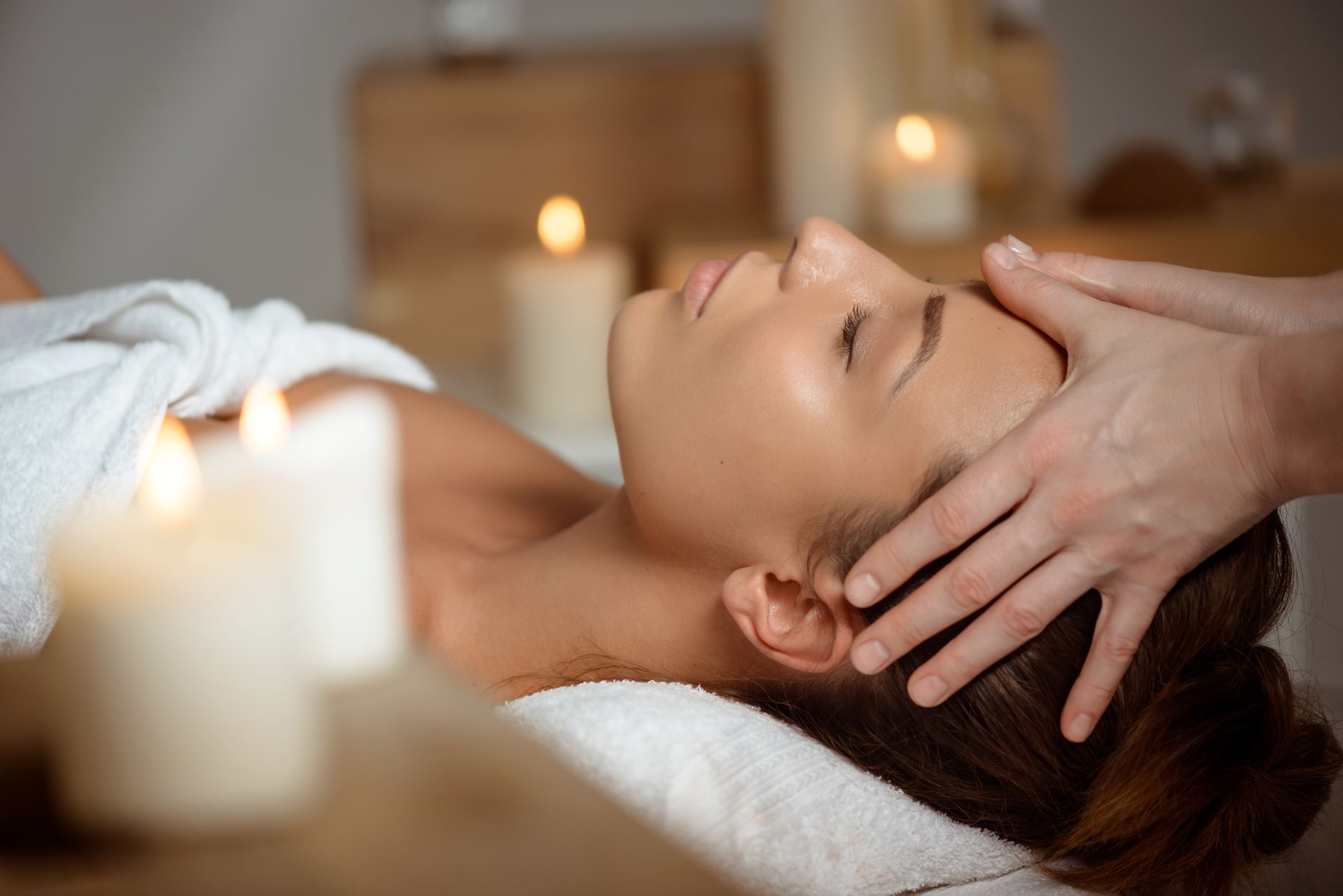a woman is getting a head massage with candles in the background