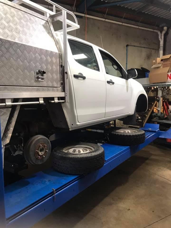 A White Truck Is Sitting On Top Of A Blue Lift In A Garage — Marcoola Tyre & Mechanical In Marcoola, QLD