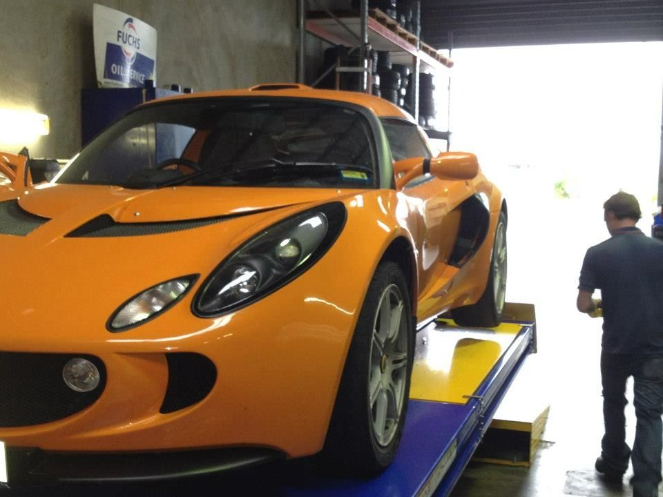 An Orange Sports Car Is On A Lift In A Garage — Marcoola Tyre & Mechanical In Marcoola, QLD