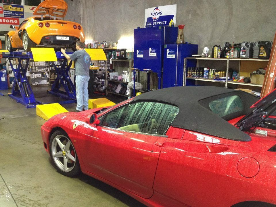 A Man Is Working On A Red Sports Car In A Garage — Marcoola Tyre & Mechanical In Sunshine Coast, QLD