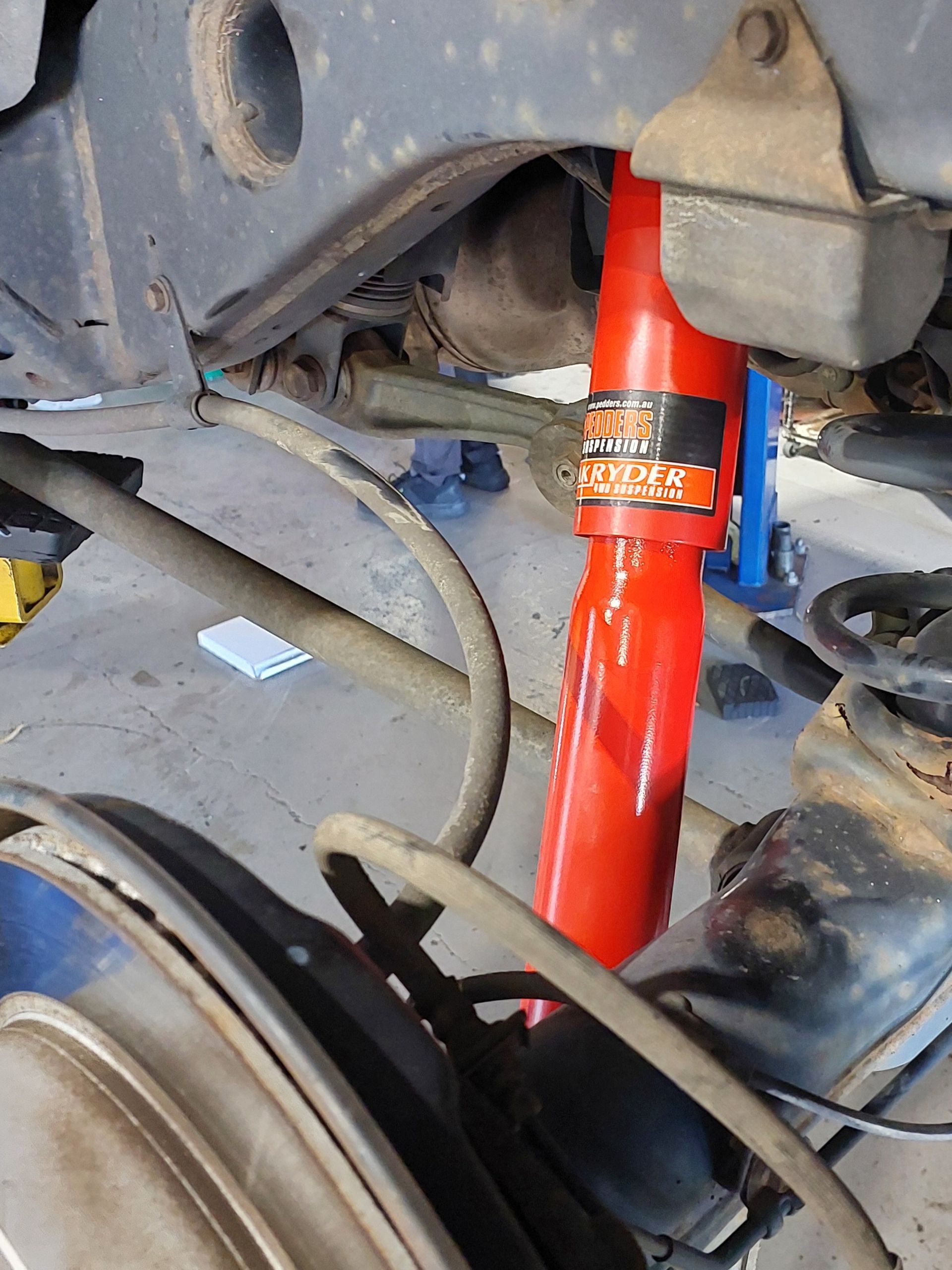 An Orange Sports Car Is On A Lift In A Garage — Marcoola Tyre & Mechanical In Marcoola, QLD