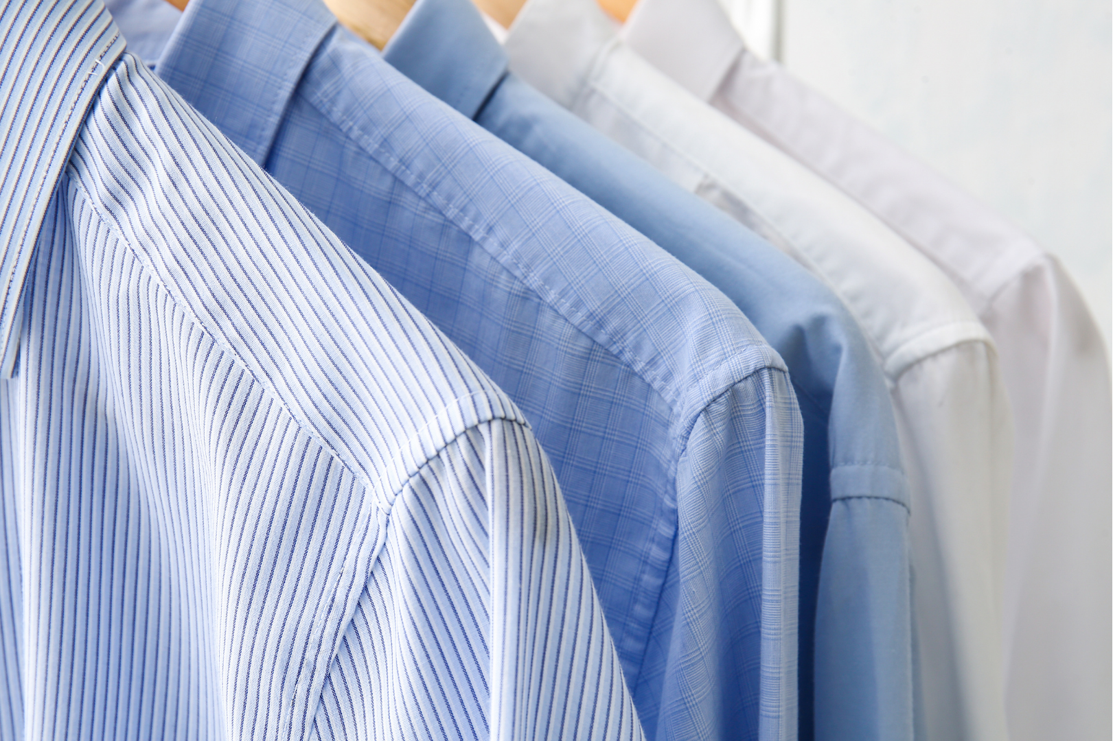 A row of blue and white shirts are hanging on a rack.