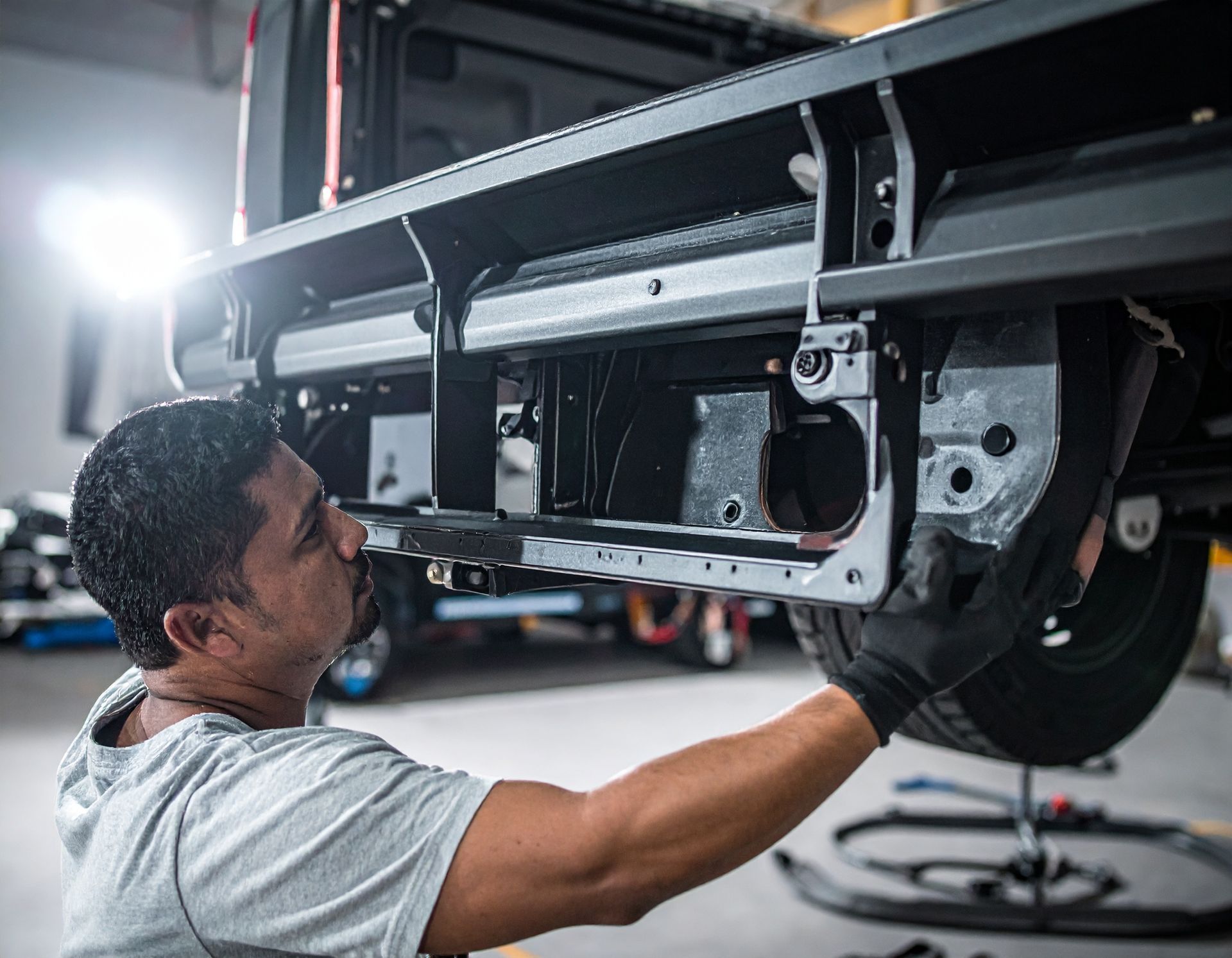 Mechanic inspecting the underside of a car on a lift in an auto repair shop