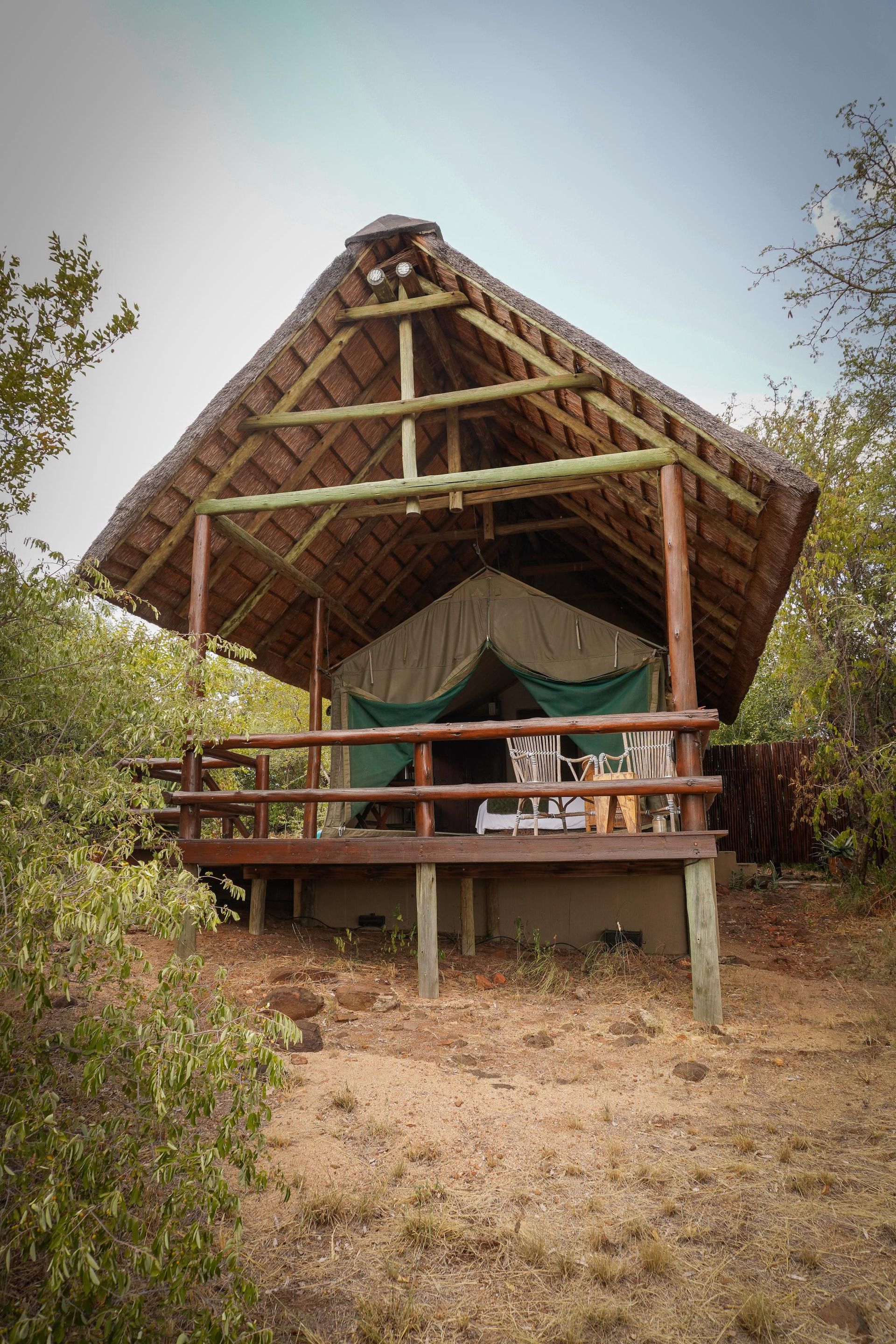 A small hut with a thatched roof is surrounded by trees.