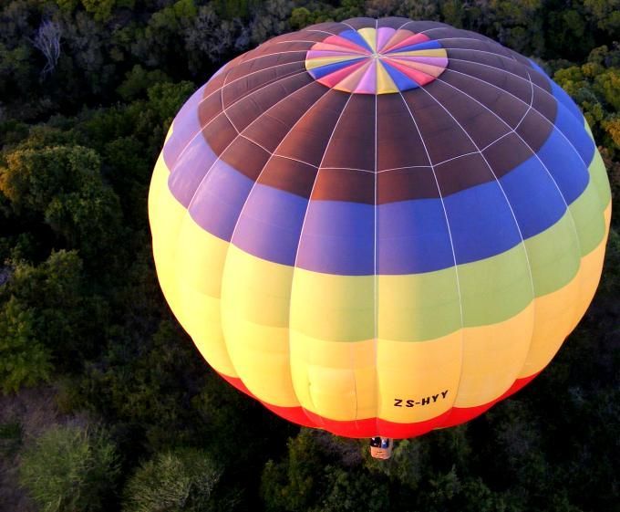 A colorful hot air balloon is flying over a forest