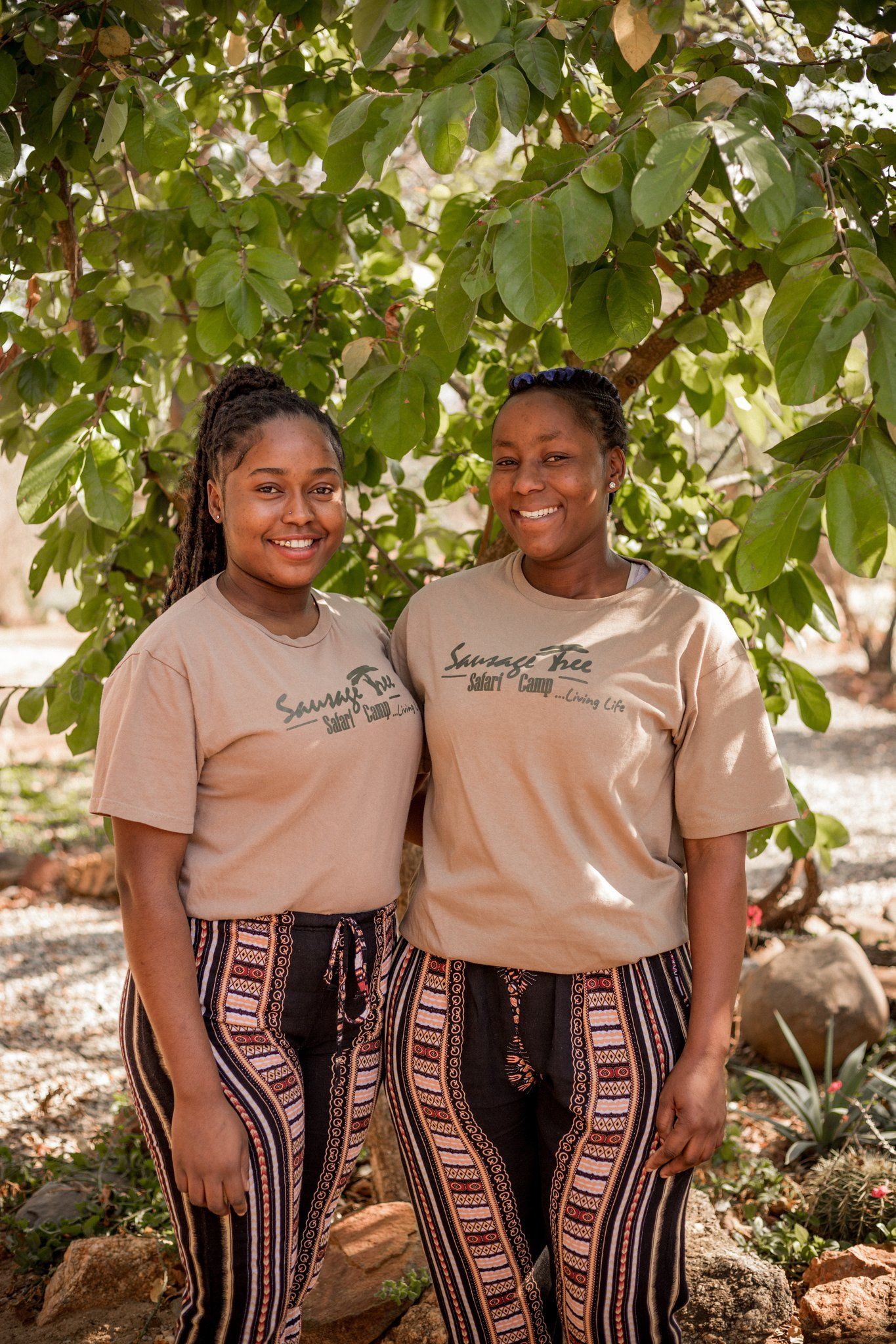 two women wearing savage tree safari camp shirts stand next to each other