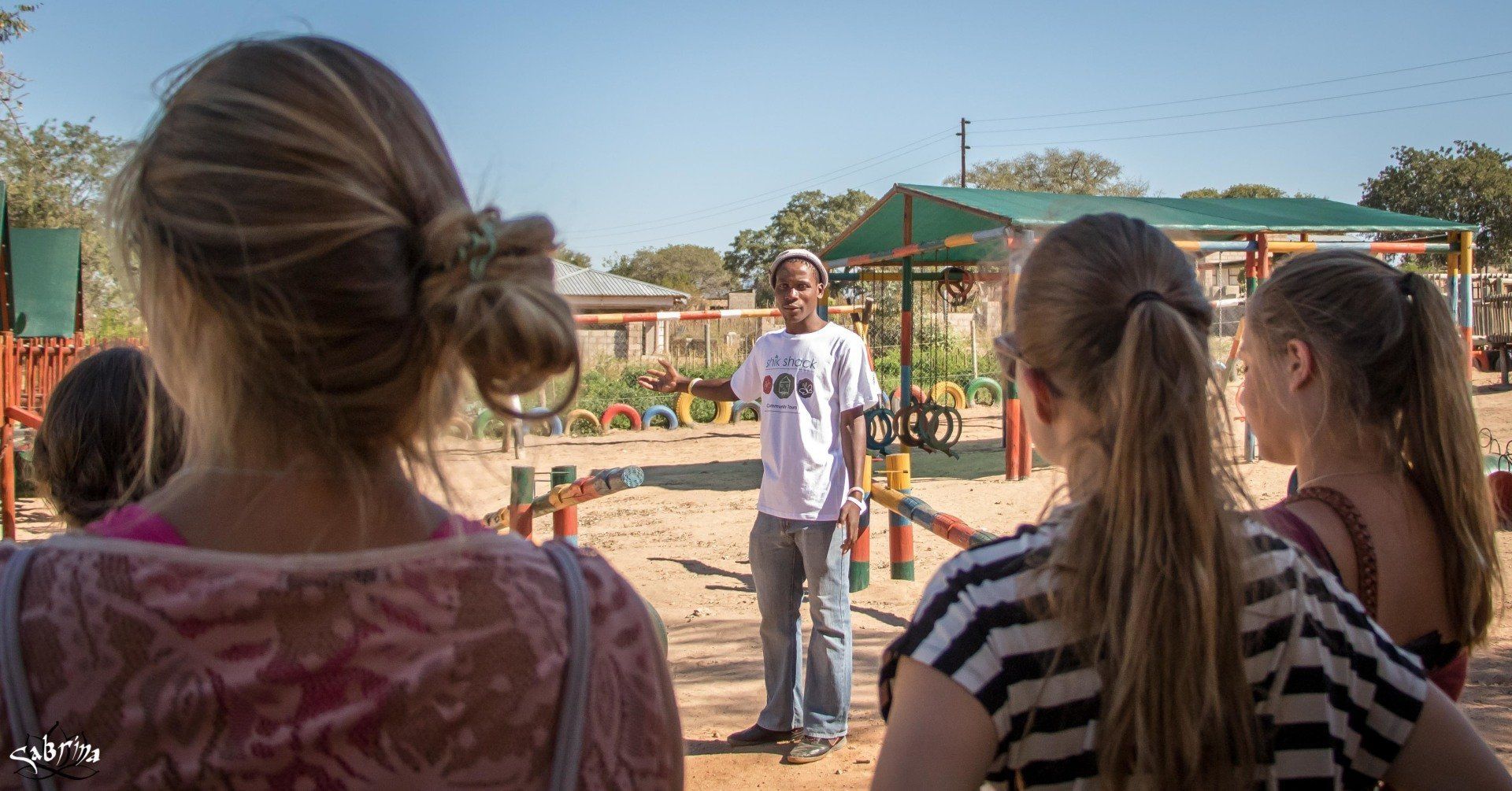 A group of people are standing in front of a playground.