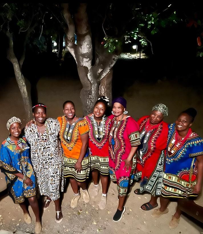 a group of women are posing for a picture with one wearing a red dress