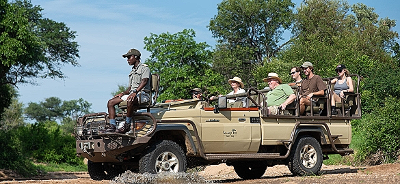a group of people are riding in a jeep on a dirt road .