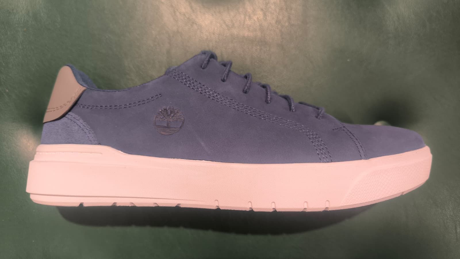 Piede di una persona con una scarpa scamosciata marrone su una scatola da scarpe. Pantaloni beige arrotolati