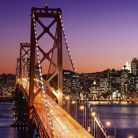 a bridge over a body of water with a city in the background