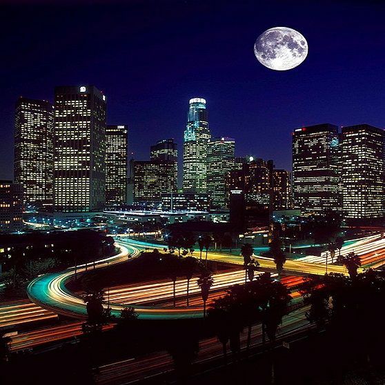 a full moon rises over a city at night