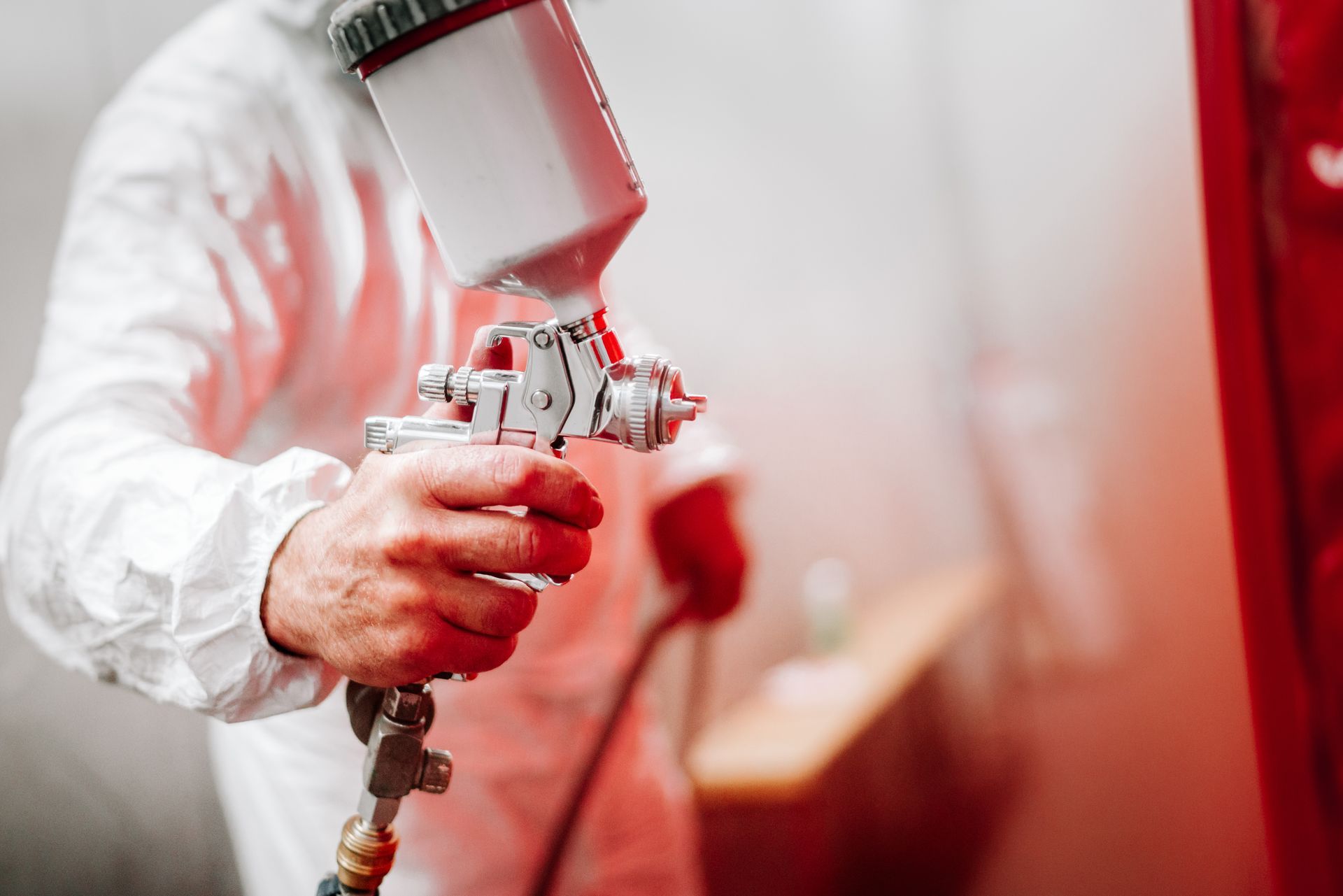 A man wearing a helmet and gloves is sandblasting a turbine.