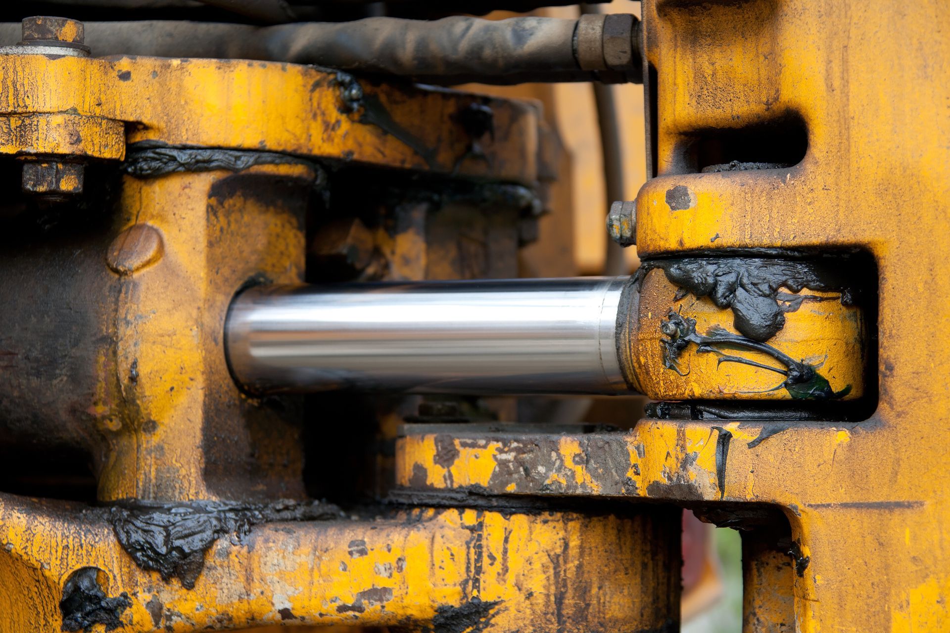 A close up of a hydraulic cylinder on a yellow machine.