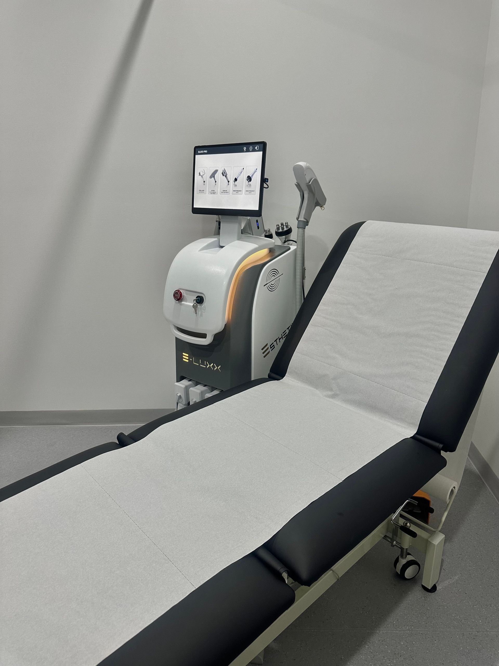 A Medical Examination Table Next To A Laser Treatment Device — Hope Laser and Beauty Clinic in Tuncurry, NSW