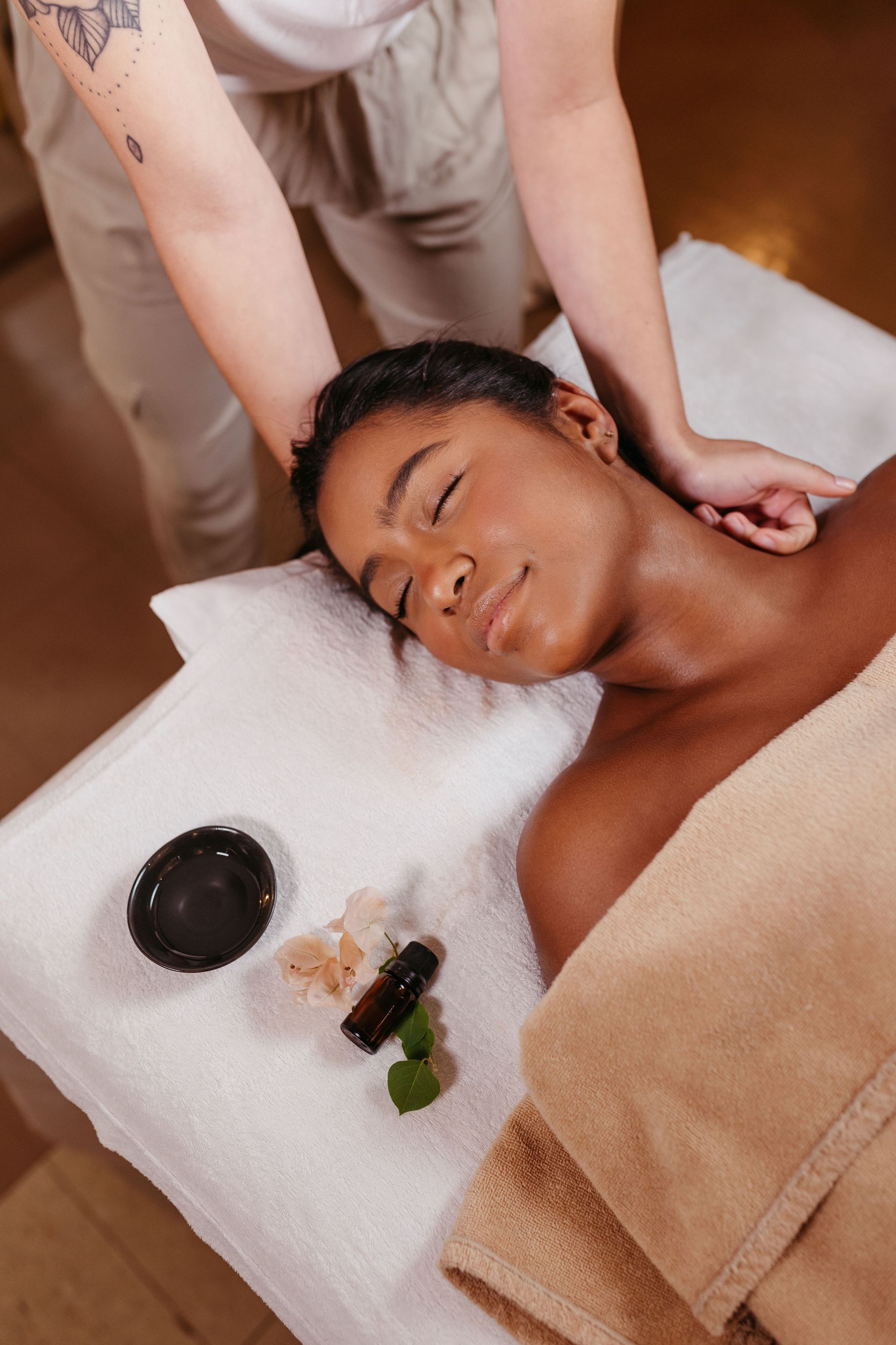 Person receiving a spa massage on a treatment table with oil and stones nearby