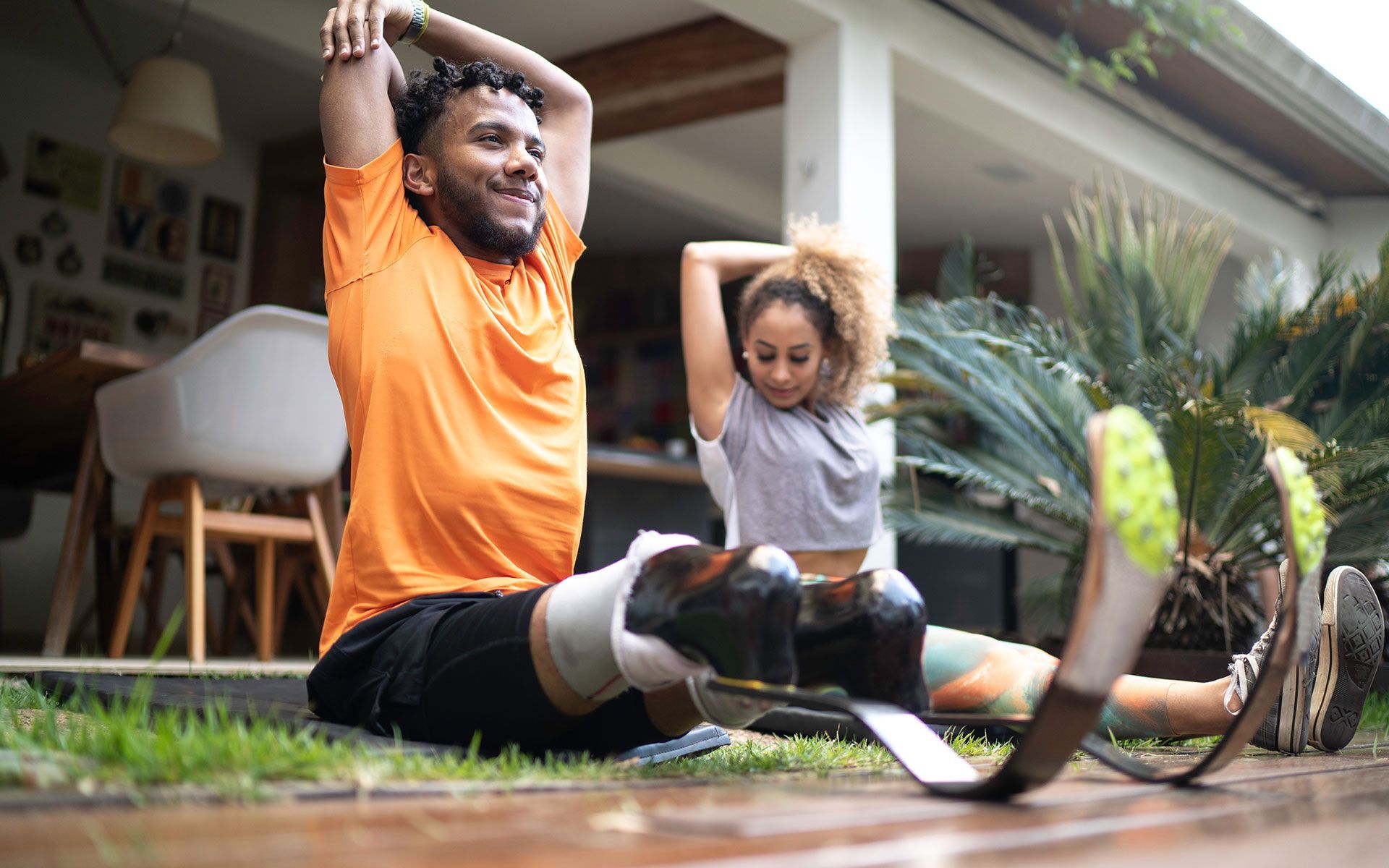A man with a prosthetic leg is stretching while a woman sits next to him.