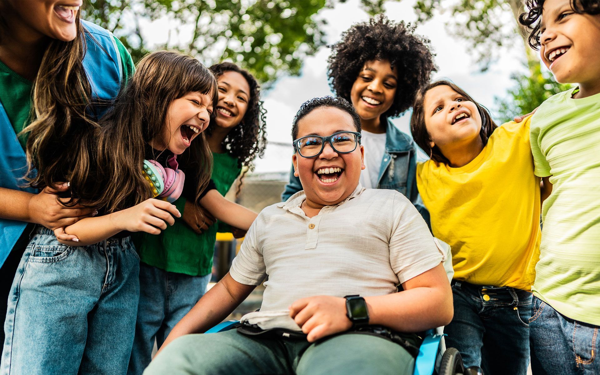 A group of children are standing around a boy in a wheelchair.