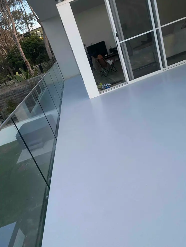 Sealed. modern balcony with glass railing and sliding doors beside a white building