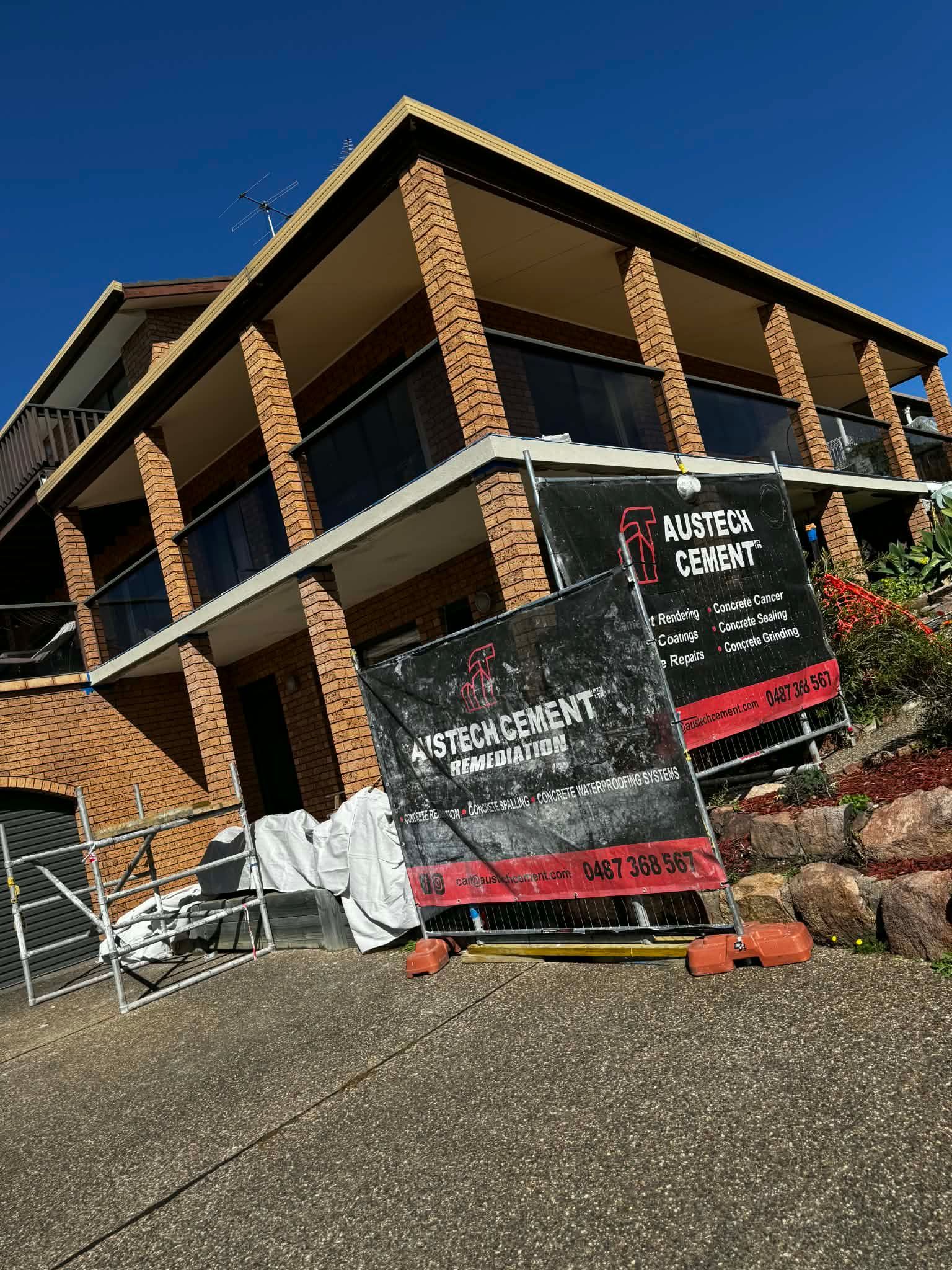 Rough brick building under construction with Austech cement signage