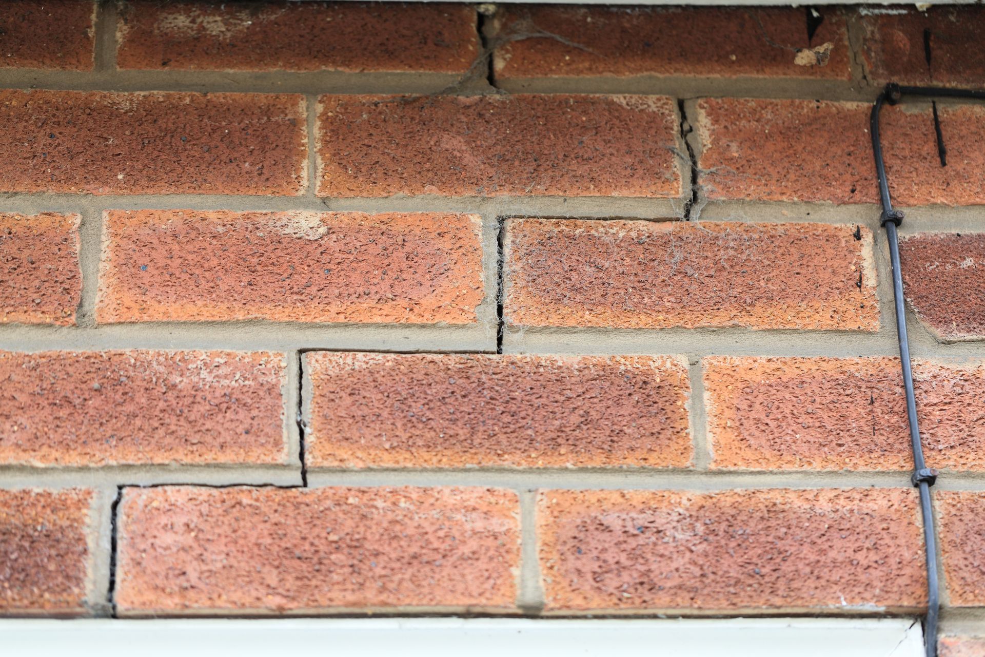 Close-up of a red brick wall with horizontal mortar lines and minor surface cracks
