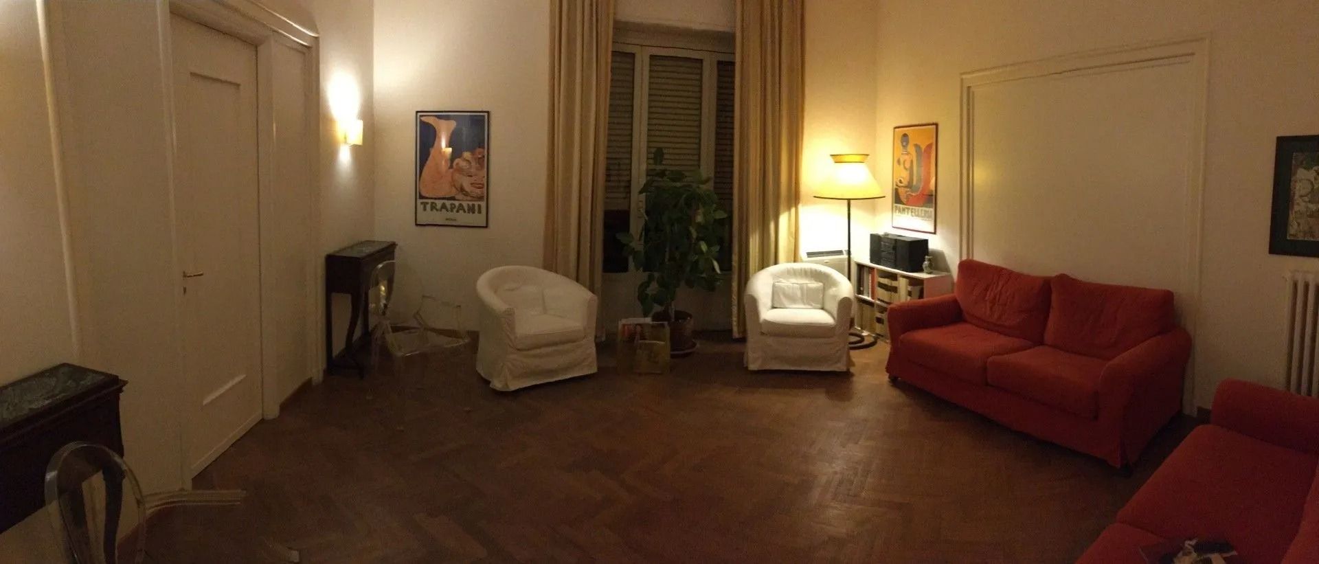Un soggiorno con pavimenti in legno, pareti bianche e divani rossi.
