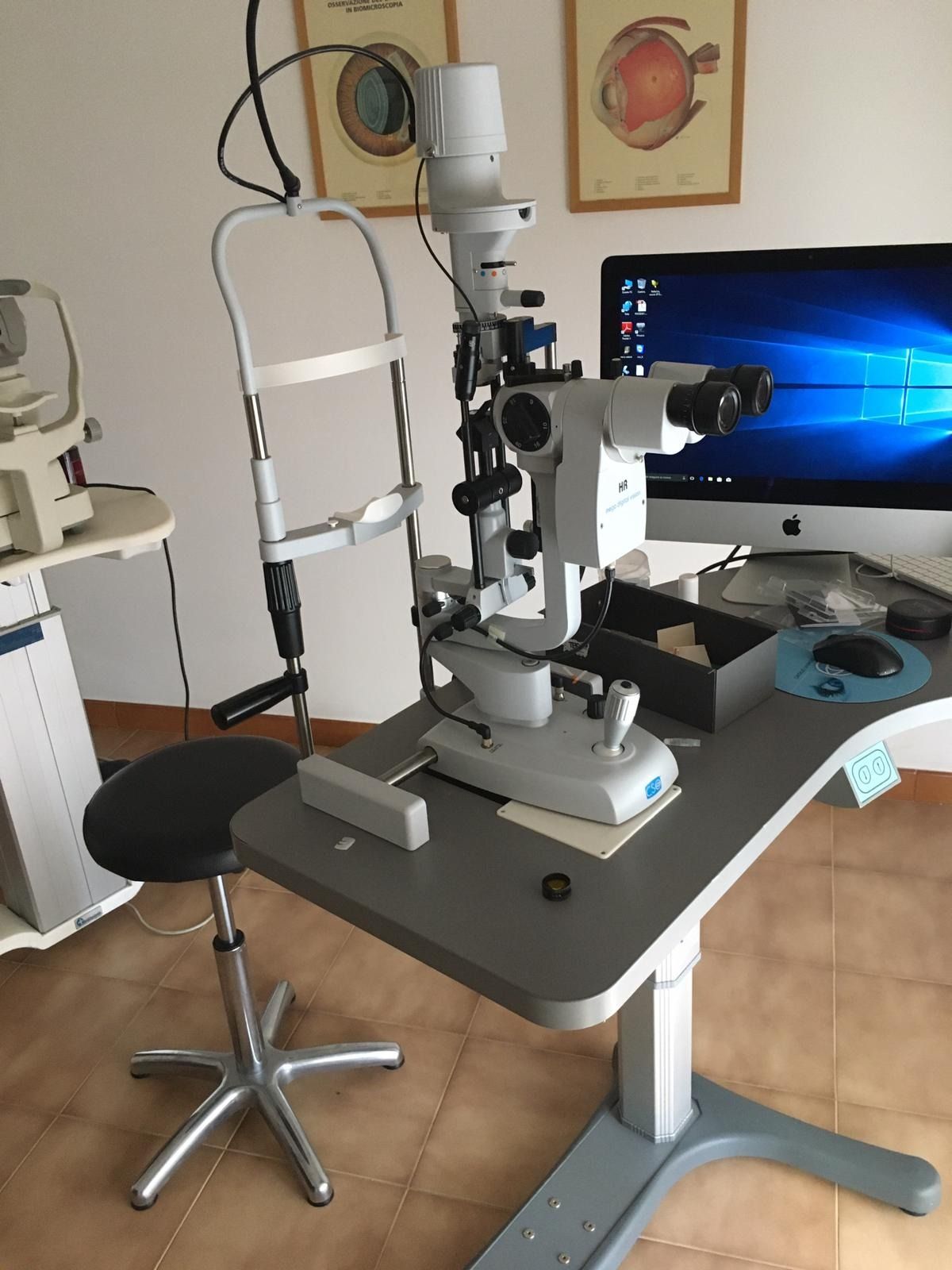 Un apparecchio per l'esame della vista dotato di sedia, computer e attrezzatura medica nello studio di un oculista.