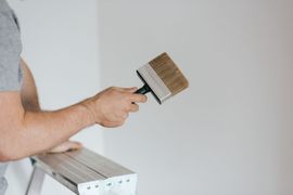 Un trabajador rocía cemento fresco sobre una pared de ladrillos en una obra de construcción.