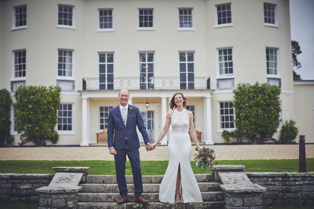 a bride and groom are holding hands in front of a large white building .