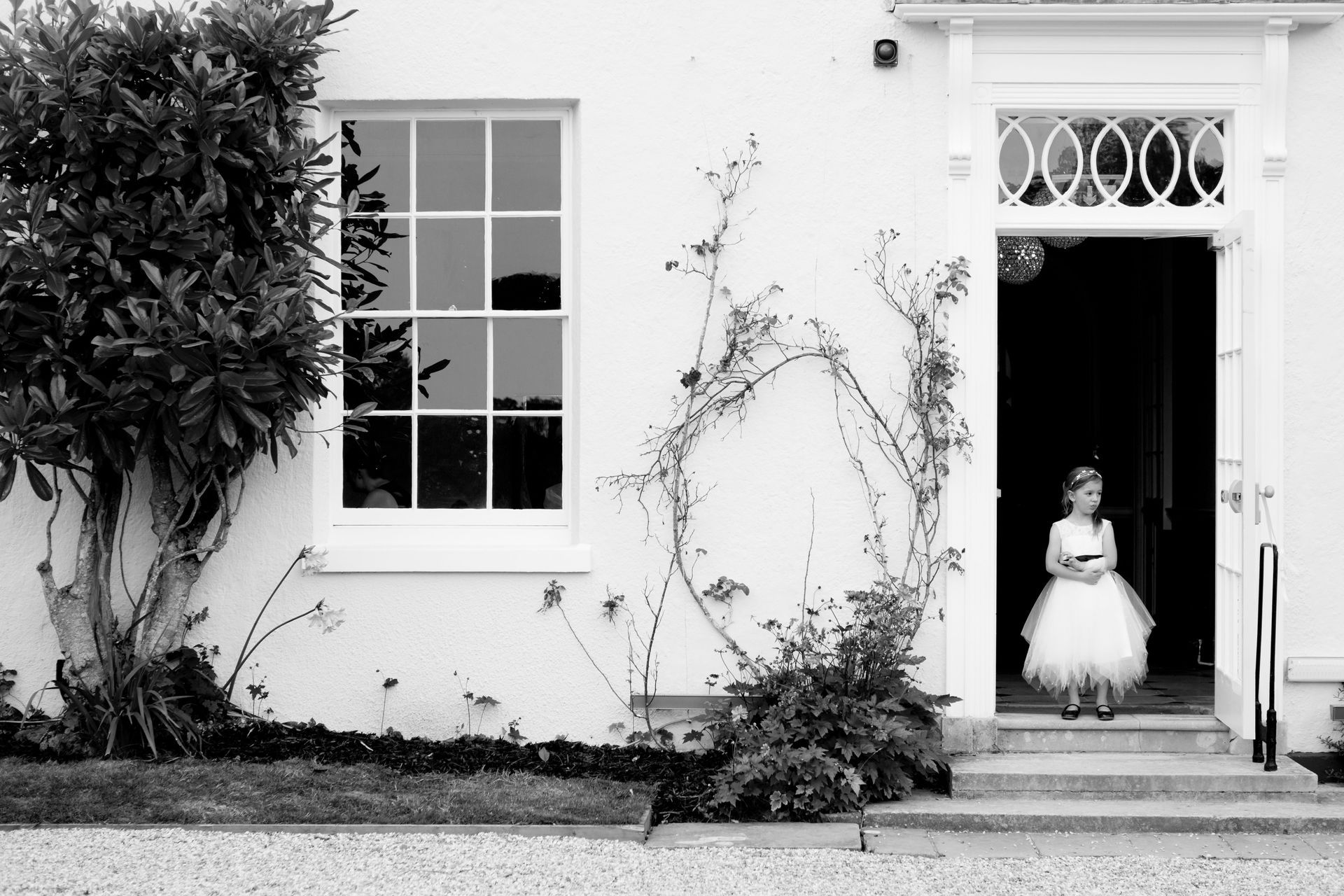 a little girl in a white dress is standing in front of a white house .