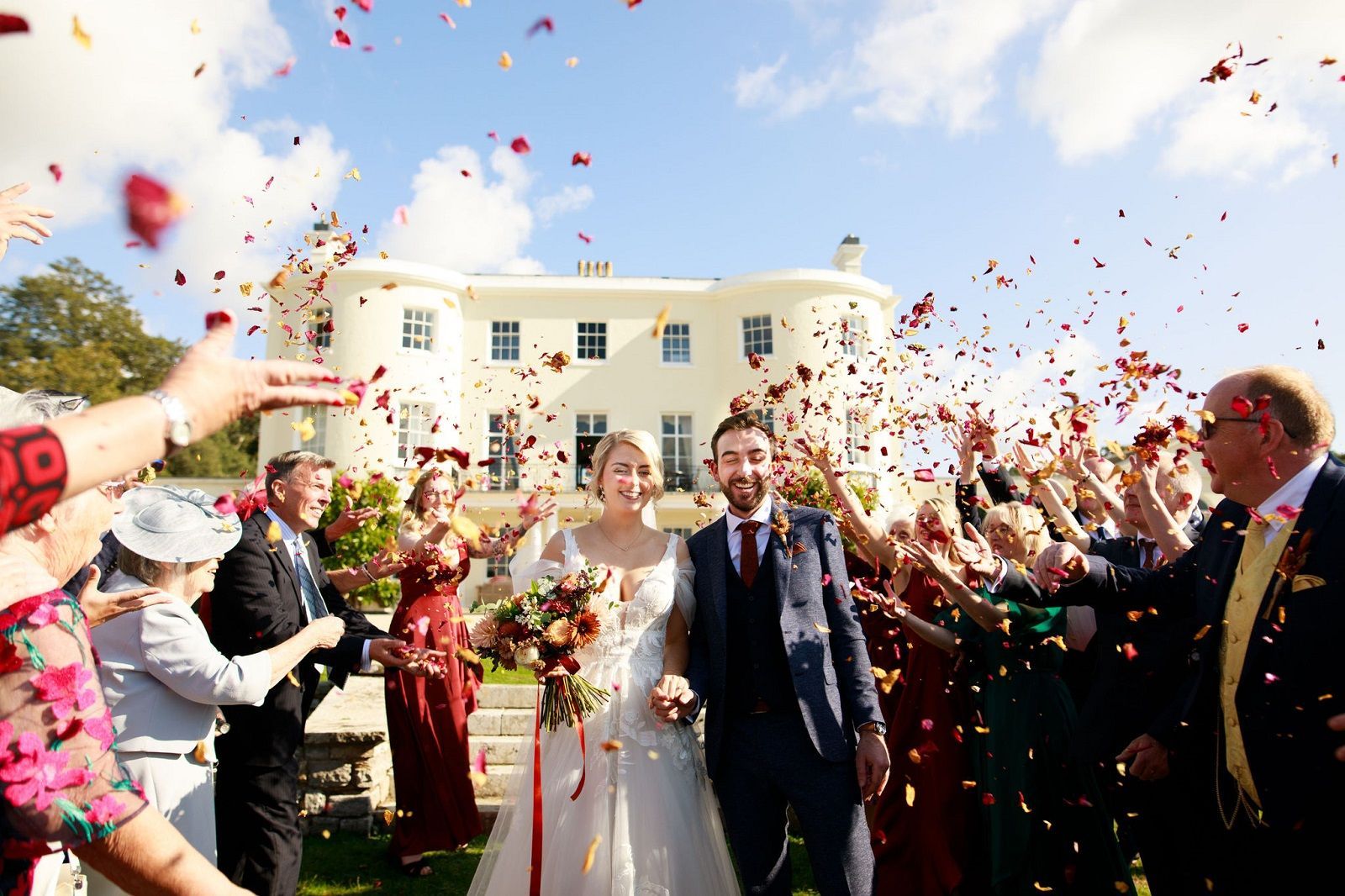 a bride and groom are walking through a crowd of people throwing confetti at them .