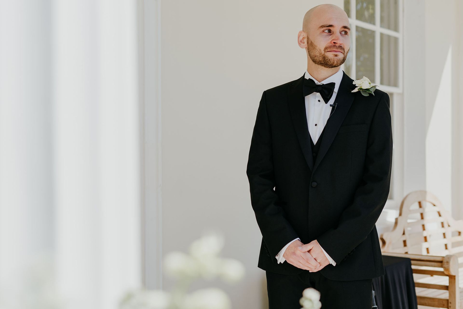 a man in a tuxedo and bow tie is standing in a room .
